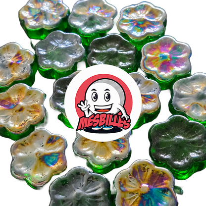 Nahaufnahme mehrerer flacher Murmeln Fleur Cosmos in Grün und Irisierend, aus Glas, angeordnet um das Logo von MesBilles.